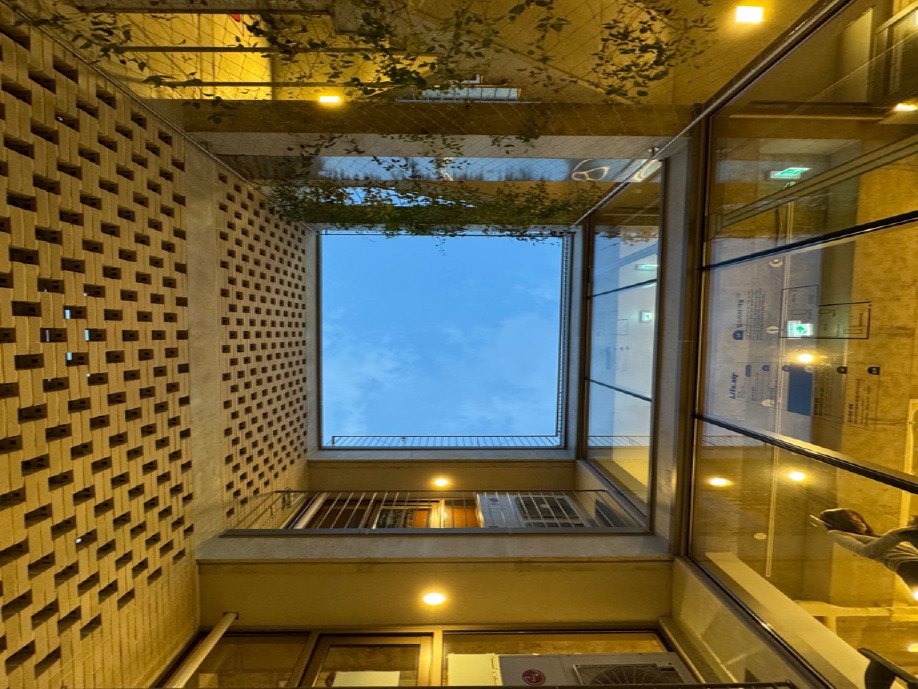 해질 무렵, 조명이 켜진 벽돌 벽과 하늘로 열린 건물 안쪽